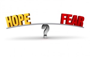 A bright, gold "HOPE" and a red "FEAR" sit on opposite ends of a gray board balanced on a gray question mark. Isolated on white.
